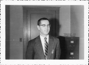 Suffolk University Athletics Director Charles Law (1946-1978), standing in front of door