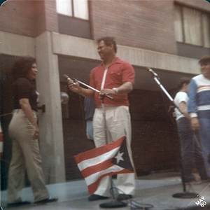 Man at a microphone with the Puerto Rican flag.
