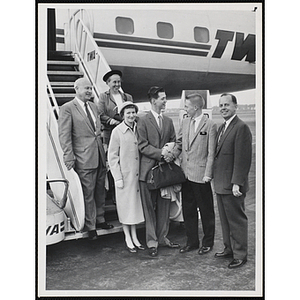 Richard J. O'Neil, Boy Ambassador, shakes hands with his brother Edward in front of an airplane while four other people stand beside them
