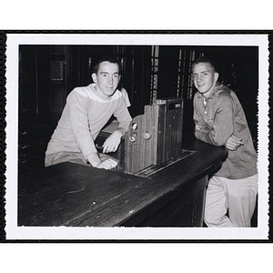 Billy Burke and Al Carlson from the Boys' Clubs of Boston posing at the desk with a cash register