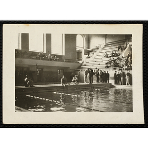 Three swimmers sit poolside during a swim meet at the Harvard University natorium