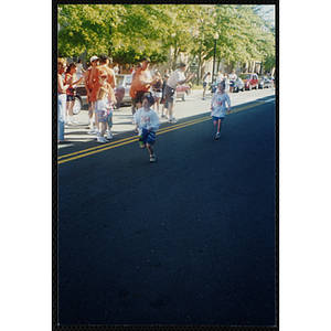 A boy and a girl run by cheering spectators during the Battle of Bunker Hill Road Race