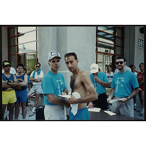 A man accepts a certificate from another man as they shake hands at the Battle of Bunker Hill Road Race