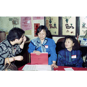 Three women chat around the sign-in table at the Chinese Progressive Association's celebration of the Chinese New Year