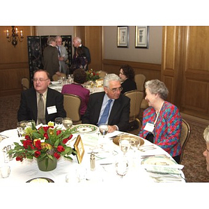 Three guests sitting at table during gala dinner to honor contributions of John Hatsopoulos, center