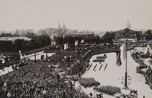 View from above of soldiers marching in formation in front of crowds of civilians in the Place de L'Etoile, Paris
