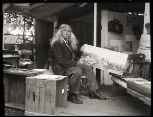 Albion L. Clough seated in his cabin, displaying a painting