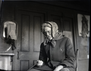 Reuben Austin Snow, the cross-dressing hermit of Cape Cod, stoking a fire in a wood stove