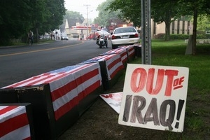 Fake caskets draped in American flags lining the road, with sign reading 'Out of Iraq'