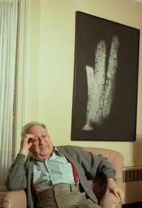 Fine art photographer Aaron Siskind seated in a armchair in his living room