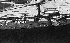 Aerial view of houses, beach, and water covered in snow