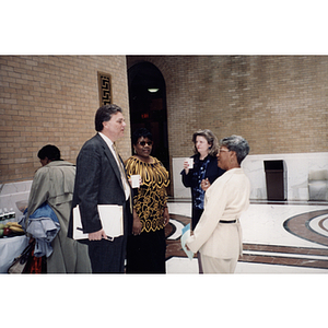 Four people stand and converse at the town hall meeting