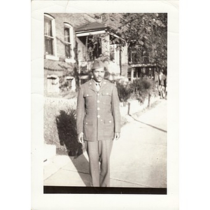 Man in soldier's uniform poses on the sidewalk