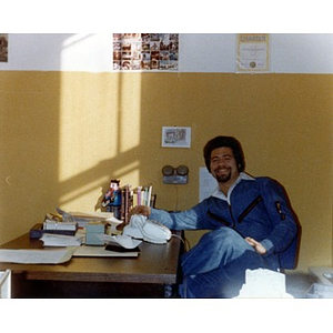 Male staff worker at La Alianza Hispana offices, seated behind a desk, smiling.