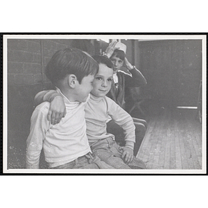 Two boys from the Boys' Clubs of Boston sit with their arms around each other while another looks on