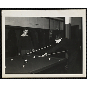 Two teenagers playing a game of pool