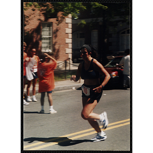 A woman passes spectators as she runs in the Battle of Bunker Hill Road Race