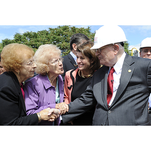 Dr. George J. Kostas shakes hands with two women at the groundbreaking for the George J. Kostas Research Institute for Homeland Security