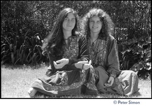 Dolma (left) and Usha (Cathy Brown): full-length portrait, seated on the ground, arms around one another