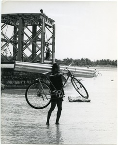 Man carrying bicycle and corrugated metal