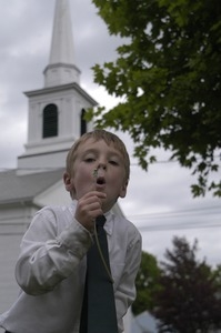 Church supper at the First Congregational Church, Whately: boy blowing on the seed head of a dandelion in front of the church