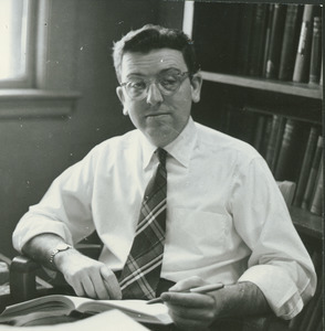 Albert E. Goss sitting indoors, working behind desk