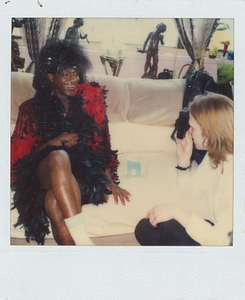 A Photograph of Marsha P. Johnson Posing for a Camera in a Black and Red Feathered Dress