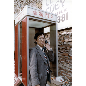 Chinese Progressive Association member speaks on a telephone in a public telephone box
