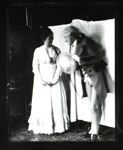 Unidentified man and woman, full-length informal portrait, standing in front of a white sheet, location unknown, undated