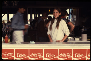 Young girl standing by the counter of food booth at a fair