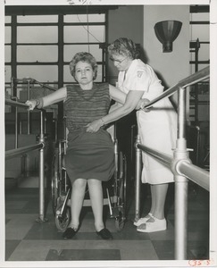 Physical therapist assisting Mrs. Frances Marsala in her use of parallel bars