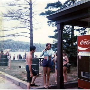 Latino youths wearing shorts and bathing suits stand next to the park facilities; the girl standing second from left is fixing her hair