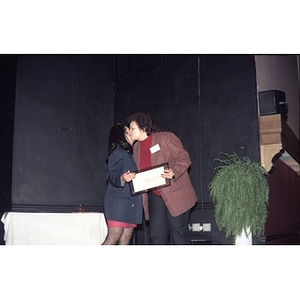 Carmen Cotto accepts a framed certificate on stage.