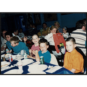 Children and adults, seated together, eat and converse at a Kiwanis Awards Night