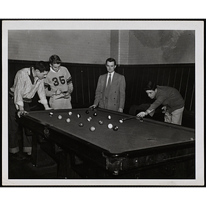 A Group of teenage boys playing a game of pool