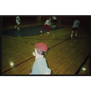 Teenagers play floor hockey on a basketball court