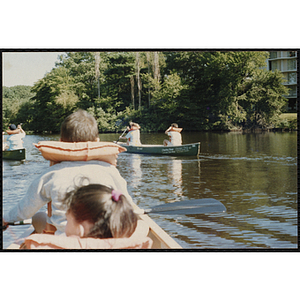 Children paddle canoes on a lake