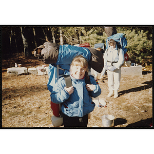 A girl wearing a backpack smiles for a shot at a camp site