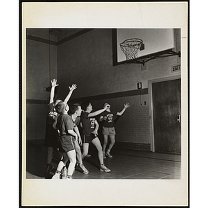 Players watch the ball above the basket during a basketball game