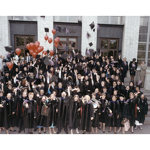 Law school graduates throwing mortarboards on the steps of Ell Student Center