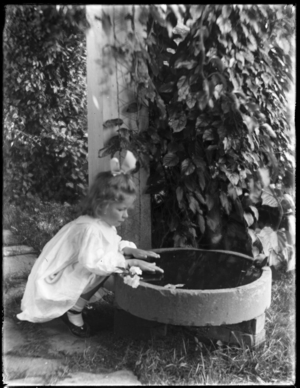 Young girl crouching by bird bath