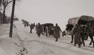 Truck, soldiers and horse-drawn artillery walking on a snow-covered road