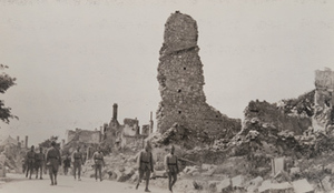 Soldiers walking along street through a badly damaged town