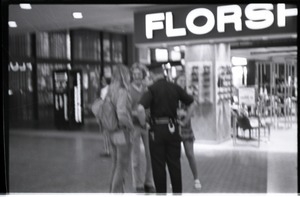 Free Spirit Press crew members talking with police office in an indoor mall