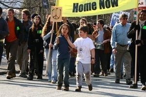 Children at the head of the march with a sign decorated with a peace symbol: rally and march against the Iraq War
