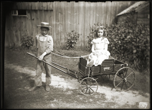 Boy pulling girl in a toy wagon (Greenwich, Mass.)