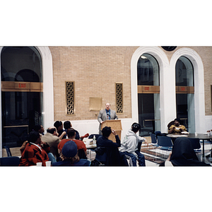 A man speaks from a lectern at a town hall meeting