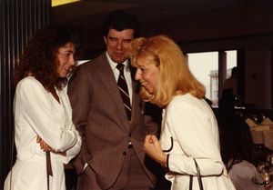 Suffolk University Athletics Director James E. Nelson laughs with two women at a university event