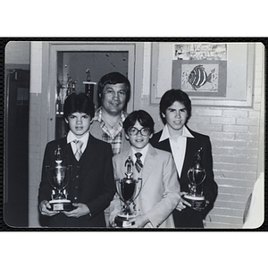 A man posing with three boys holding their trophies at a Boys' Clubs of Boston Awards Night