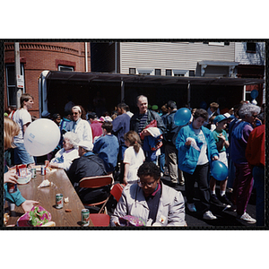 Children and their families sit and stand in front of the carnival games booths at the Boys and Girls Clubs of Boston 100th Anniversary Celebration Street Fair